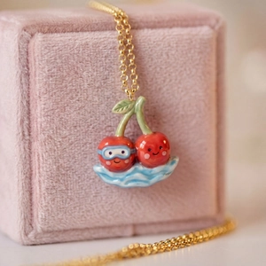 Detail of 14K gold plated necklace featuring cute red cherry pendants with blue goggles