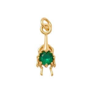 Golden beetle jewelry pendant with a faceted green gemstone in a centered flat lay view