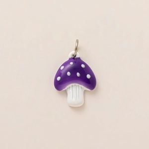 Détail macro d'un pendentif champignon violet à pois blancs avec anneau doré pour bijoux DIY