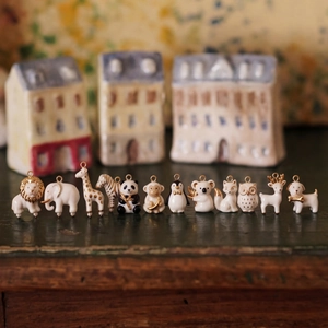 Macro shot of twelve animal-shaped ceramic pendants featuring exquisite gold-painted details