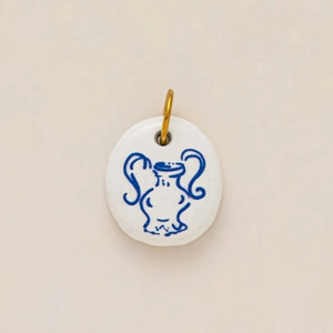 Detalle del colgante redondo de cerámica blanca con diseño de ánfora azul y gancho