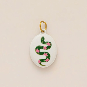 Detalle de un colgante ovalado de esmalte blanco con serpiente verde y estrellas rosas