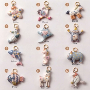 Close-up of 12 animal pendants with colorful oil-drop prints and golden rings for DIY