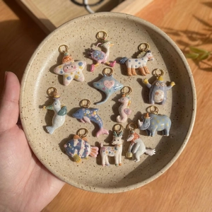 Handcrafted ceramic animal pendants with colorful floral patterns on a ceramic tray