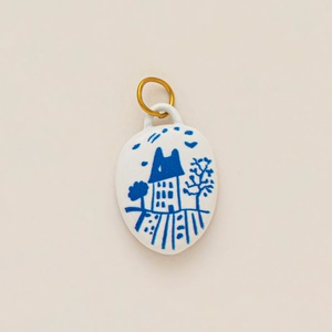 Detail of handmade ceramic oval pendant with blue landscape art and gold metal ring