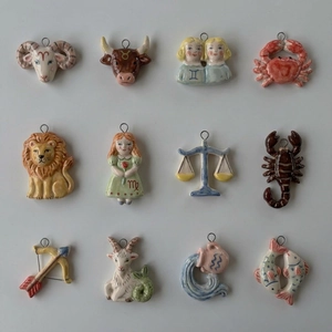 Macro shot of 12 colorful ceramic zodiac charms with gold-plated metal loops