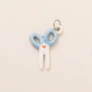 Detailed view of scissor-shaped ceramic pendant with blue handles and red heart