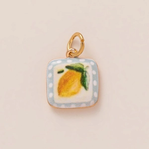 Macro shot of square enamel lemon pendant charm with blue polka dot border and gold ring