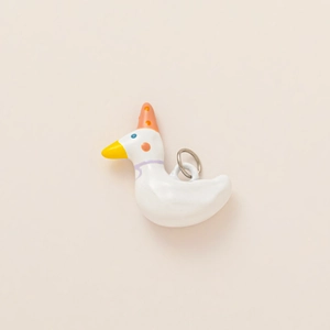 Close-up of a white ceramic duck pendant wearing a polka dot party hat and a purple neck tie
