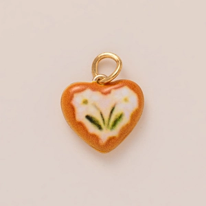 Close-up of heart-shaped pendant with orange enamel finish and delicate floral pattern