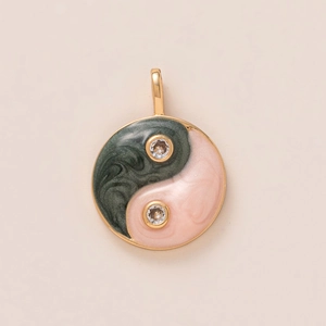 Macro detail of gold plated Tai Chi pendant with green and pink enamel and zircon stones