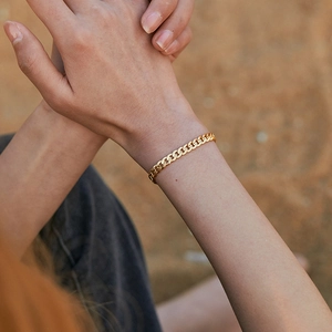 Classic 18K gold plated brass Cuban link bracelet for women on a textured outdoor background