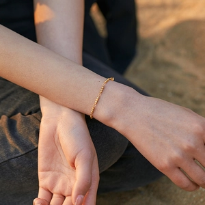 Minimalist 18K gold plated beaded chain bracelet worn on wrist in warm outdoor lighting