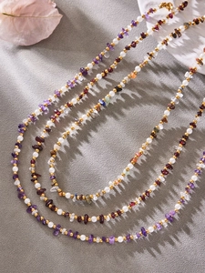 Detailed close-up of handmade necklace with natural gemstones, pearls and gold beads