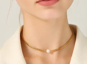Detail of a gold Cuban link chain necklace with a centered white freshwater pearl on model