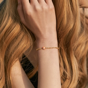 Fashionable 18K gold-plated brass bracelet with orange evil eye bead on female wrist