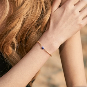 Detailed close-up of handmade 18K gold-plated beaded bracelet with Evil Eye charm on wrist
