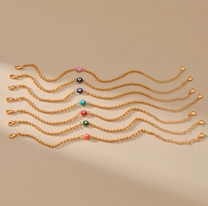 Detalle de siete pulseras de ojo turco con dijes de esmalte de colores y perlas doradas