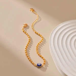 Detalle de la cadena de bolas doradas con colgante de esmalte azul del ojo turco