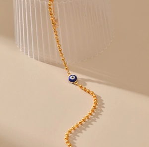 Primer plano detallado de una pulsera de cadena dorada con dije de ojo turco azul