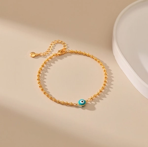 Detalle de la pulsera de cuentas doradas con dije de ojo turco azul y cierre de mosquetón