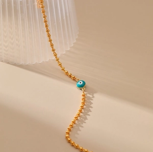 Vista detallada de la pulsera de cuentas doradas con amuleto de ojo turco azul