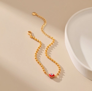 Detalle de la pulsera de cuentas doradas con amuleto de ojo turco rojo y cadena ajustable