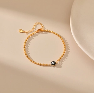 Vista detallada de pulsera de cuentas doradas con ojo turco y cadena de extensión