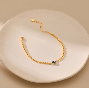 Detalle de la pulsera de cuentas doradas con dije de Ojo Turco y cadena ajustable