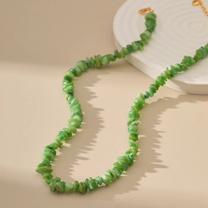 Ketting met groene natuurstenen en gouden sluiting op een witte displaystandaard
