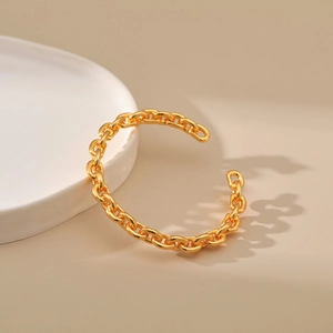 Close-up of thick gold O-chain link open cuff bracelet with high-polish mirror finish