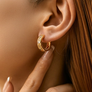 Elegante 18K vergoldete gedrehte Creolen mit Zirkonia, präsentiert am Ohr des Modells