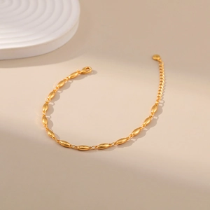 Detail of adjustable gold metal oval bead bracelet with lobster clasp and extension chain