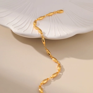 Minimalist gold link bracelet with oval beads on white ceramic tray for women