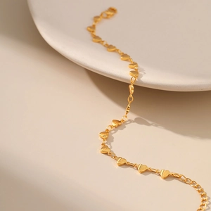 18K gold-plated heart link chain bracelet for women on white ceramic plate