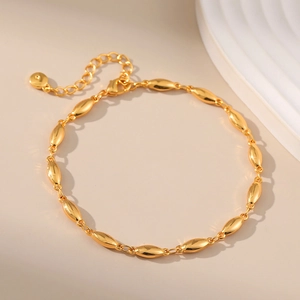 Minimalist gold chain bracelet with oval beads and adjustable clasp on beige surface