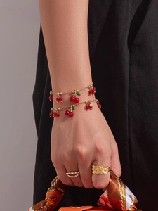 Dettaglio di braccialetti a ciliegia e anelli floreali indossati da una modella