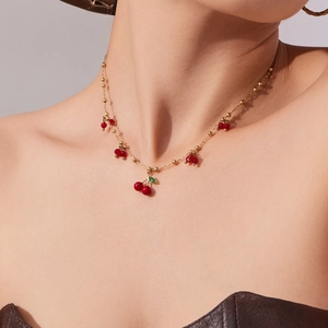 Collana con ciondolo a ciliegia, perle di vetro rosse e catena d'oro su modella