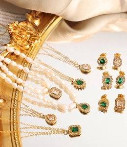 Colliers en perles baroques et parure de boucles d'oreilles émeraude sur fond soie