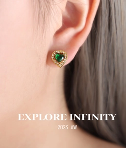 Gros plan sur une boucle d'oreille en or avec gemme en cœur vert et halo de diamants