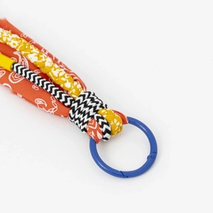 Detail of colorful woven cord keychain with orange paisley fabric and blue metal ring