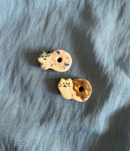 Detail of two ceramic cat figurines with strawberry and chocolate donut patterns