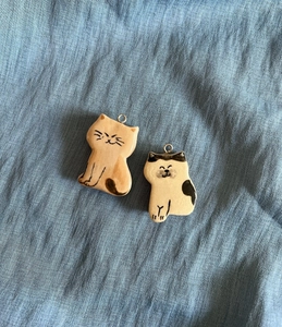 Detail of two handmade ceramic cat pendants with colorful hand-painted patterns