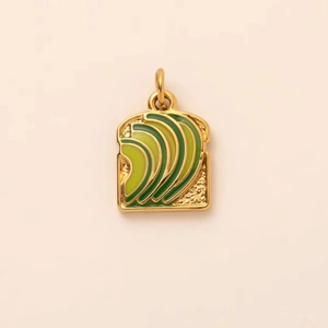 Détail du pendentif toast à l'avocat avec placage d'or et finition émail vert