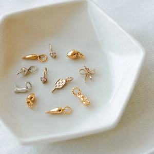 Elegante Sammlung von Gold- und Silberanhängern mit Herzen und Schleifen in Keramikschale