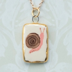 Ciondolo in oro 18 carati con una lumaca rosa dipinta a mano su inserto in ceramica