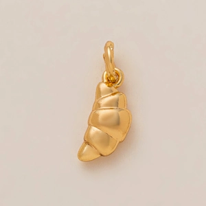 Detailed macro view of a golden croissant pendant featuring textured spiral metallic patterns