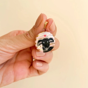 Close-up of hand-painted round pendant with black sheep and red heart in 18K gold plating