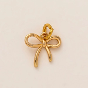 Detailed macro view of a polished 18K gold-plated bow-shaped pendant charm