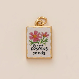 Detail of a rectangular cosmos flower pendant with finest seeds text on gold metal base